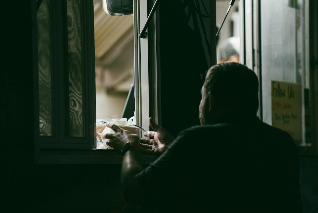 person reading book by window at night